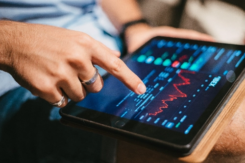 Qué son los CFDs: trader revisando datos del mercado bursátil en una tablet