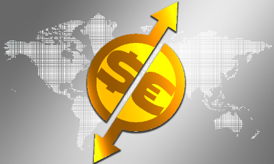 Una composición de billetes de dólares y yuanes, monedas doradas y un llavero del globo sobre informes financieros.