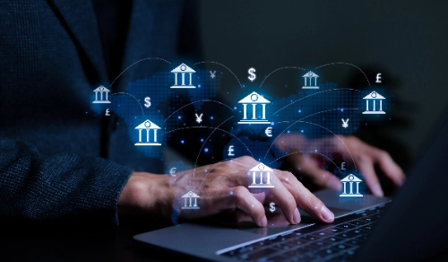 Manos de un profesional escribiendo en una laptop bajo una interfaz flotante. La red digital muestra bancos centrales interconectados y símbolos de divisas.