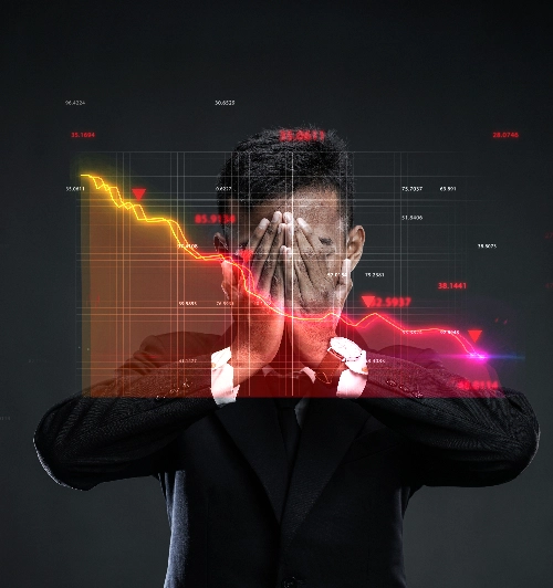 Un hombre de negocios con traje oscuro se cubre el rostro con las manos con gesto de desesperación, detrás de un gráfico digital lineal rojo translúcido que muestra una fuerte caída financiera.