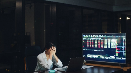 Mujer trabajando hasta tarde, agotada frente a la laptop