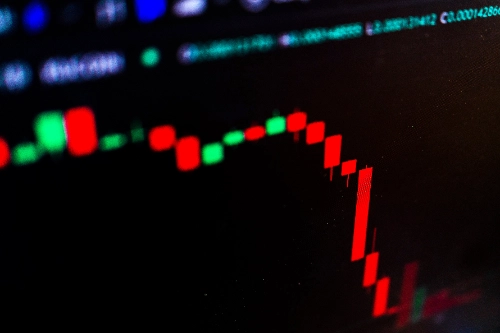 Primer plano de una pantalla que muestra una caída drástica en un gráfico de velas financieras rojas.