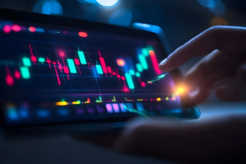 Una mano interactúa con una tableta digital que muestra gráficos de velas financieras brillantes en tonos verdes y rojos.